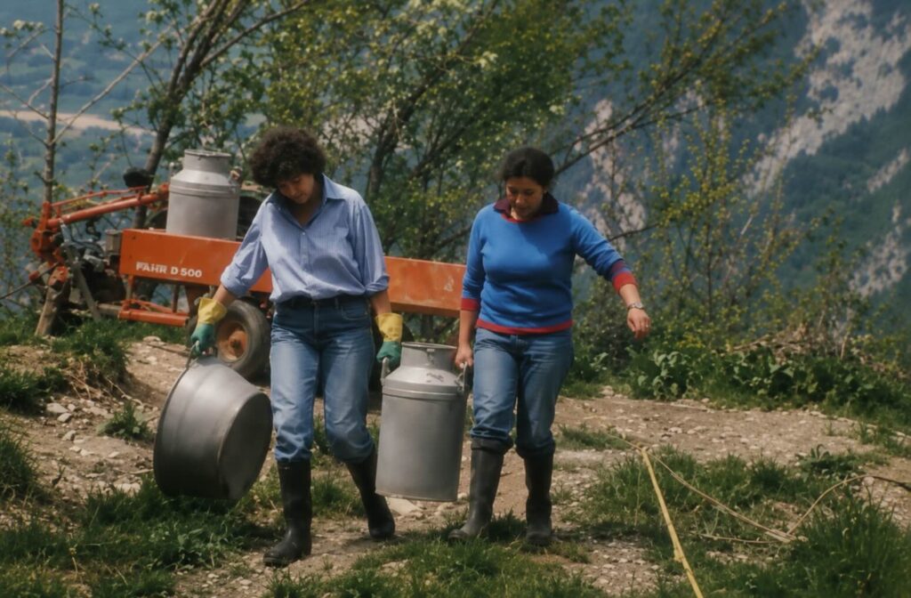 Deux femmes agricultrices transportant des bidons de lait dans une exploitation agricole en Valais en 1983.